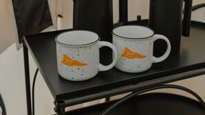 Une table avec deux tasses blanches, une cafetière noire et une cafetière à piston.