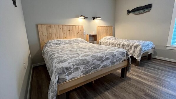 A bedroom with two beds, wooden headboards, a fish wall decoration, and a window with blinds.
