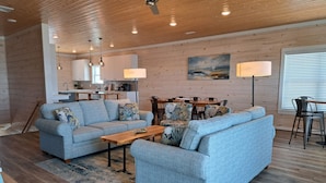 A modern living room with a sofa, coffee table, and dining area. - Stunning Oceanfront Retreat w/ Private Pool, Elevator, Handicap Accessibility (Ocean Isle Beach)