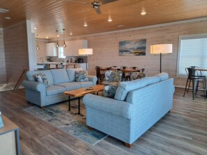 A modern living room with a sofa, coffee table, and dining area. - Stunning Oceanfront Retreat w/ Private Pool, Elevator, Handicap Accessibility (Ocean Isle Beach)