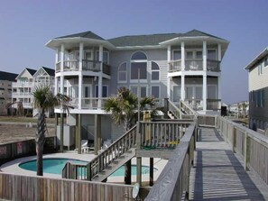 A beachfront hotel with multiple balconies, a pool, and a wooden boardwalk. - Oceanfront Paradise with Pool, Elevator & Views! By Williamson Realty (Ocean Isle Beach)