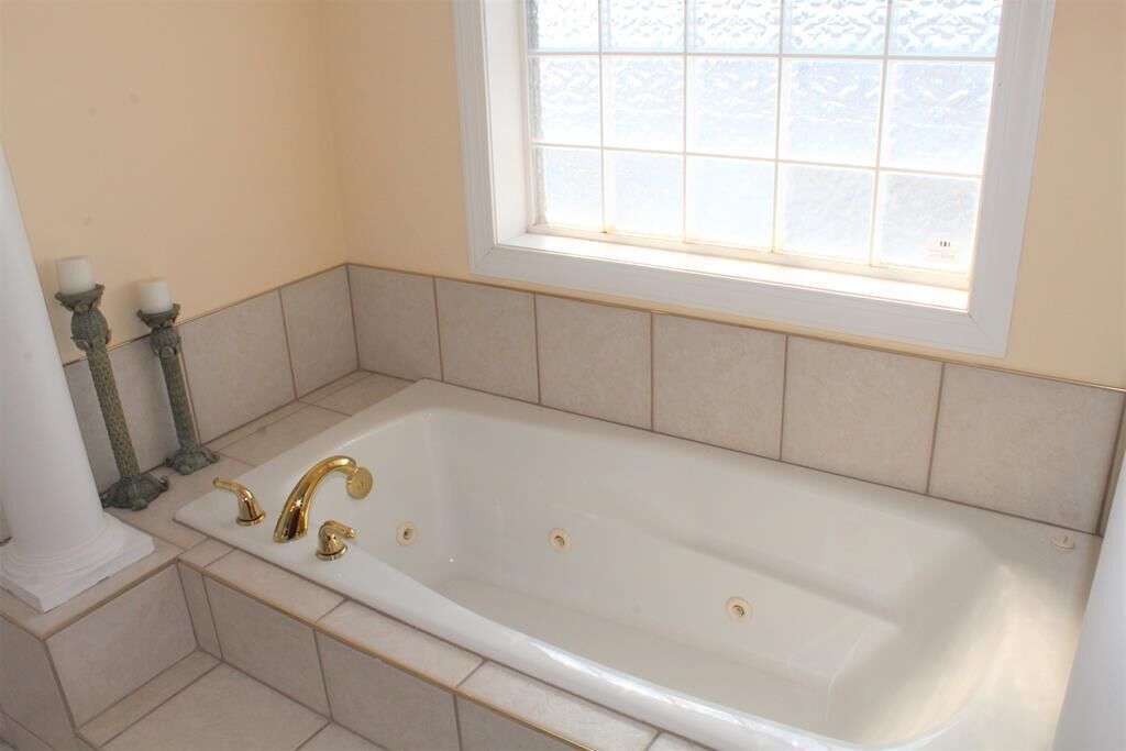 Une salle de bain avec une baignoire sur pieds, deux appliques murales et une fenêtre située au-dessus de la baignoire.