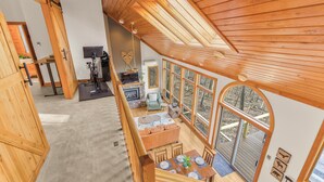 Un vaste espace de vie aménagé dans un style industriel, avec une grande table à manger, un coin salon confortable et une vue sur l’extérieur.