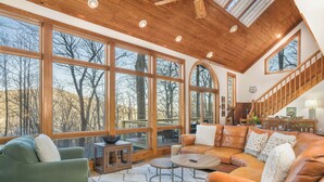 Un salon spacieux avec de grandes fenêtres, un plafond en bois et un canapé en cuir.