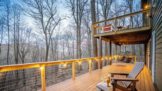 Une terrasse en bois avec des sièges d’extérieur, une rambarde et des guirlandes lumineuses.