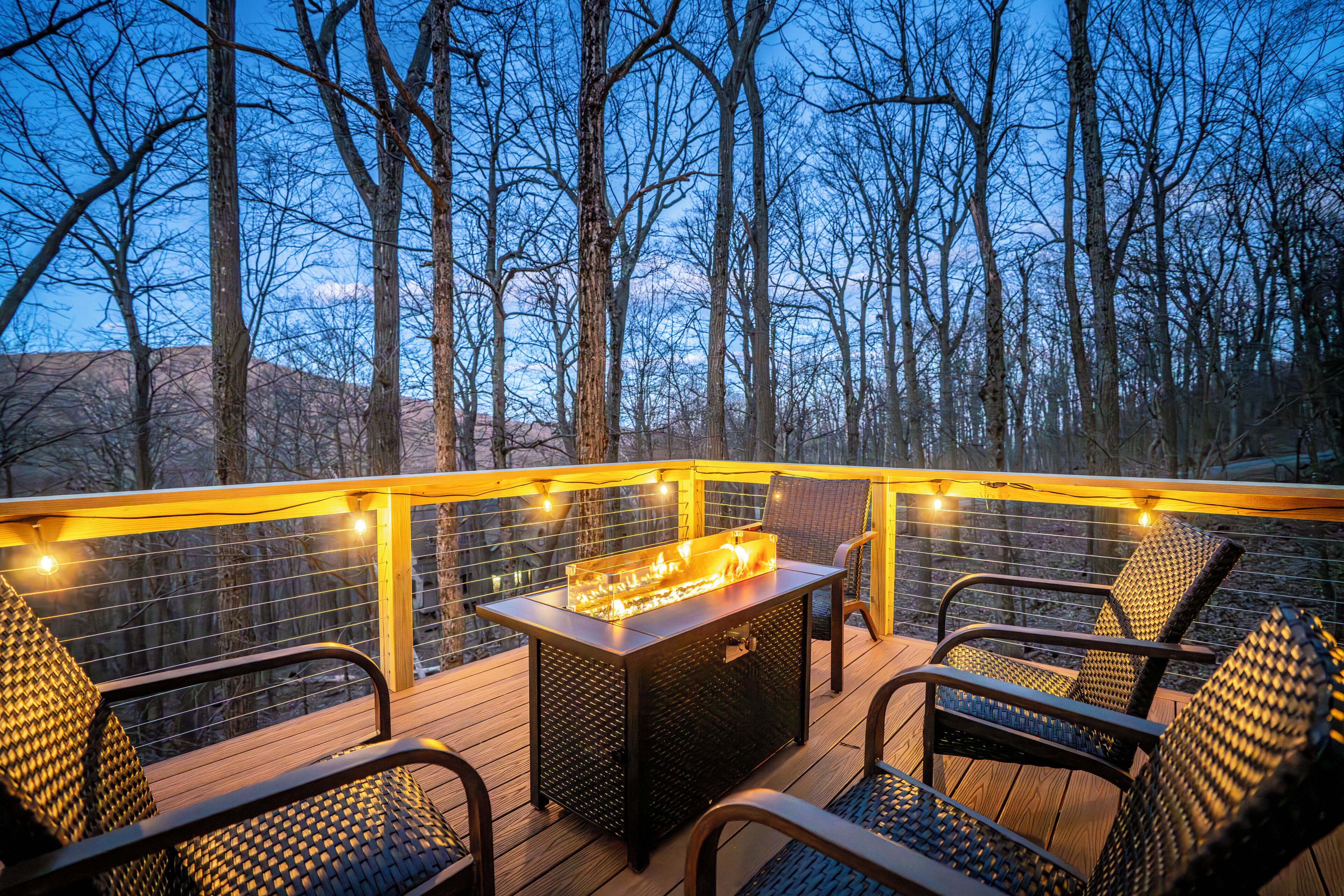 A deck with a fire feature, chairs, and a railing.
