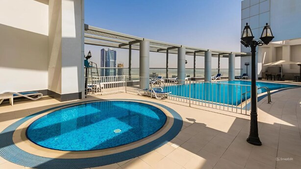 A rooftop swimming pool with a glass balustrade, lounge chairs, and a view of a city skyline. - Burj Khalifa DownTown Hostell (Dubai)