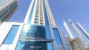 A high-rise building with a modern glass facade and a prominent entrance with a metal canopy. - Burj Khalifa DownTown Hostell (Dubai)