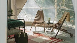 A cozy room with a large window, a bed, a chair, a small table, and a bag. - Field Trip Unit 18 GeoDome (Travelers Rest)