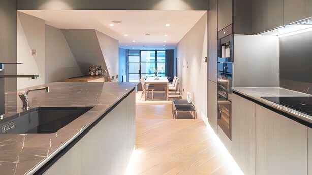 A modern kitchen with a central island, built-in appliances, and a dining area with natural light. - Soho Living 2-Bedroom Apartment in Soho (London)