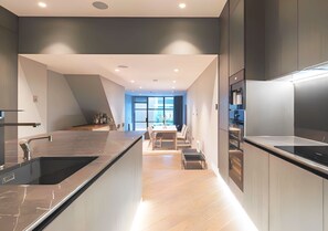 A modern kitchen with a central island, built-in appliances, and a dining area with natural light. - Soho Living 2-Bedroom Apartment in Soho (London)