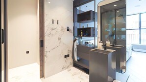 A modern bathroom with a marble wall, a large mirror, and a built-in shelf with toiletries. - Soho Living 2-Bedroom Apartment in Soho (London)