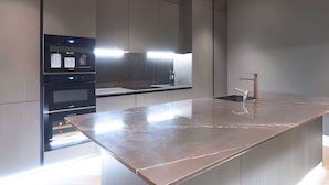 A modern kitchen with a large island, built-in oven, and a sleek faucet. - Soho Living 2-Bedroom Apartment in Soho (London)