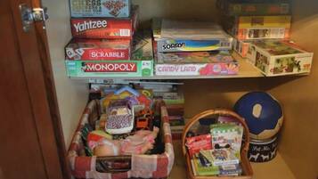 Una repisa con juegos de mesa como ajedrez, Scrabble y Monopoly.