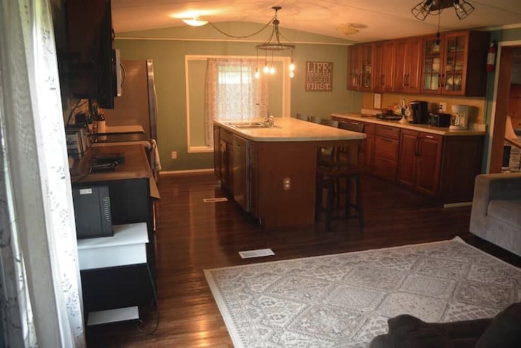A kitchen with wooden cabinets, a central island, and a dining area with a table and chairs.