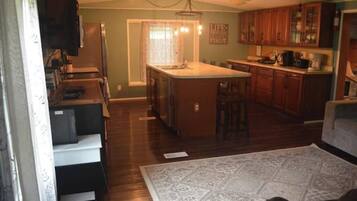 A kitchen with wooden cabinets, a central island, and a dining area with a table and chairs.