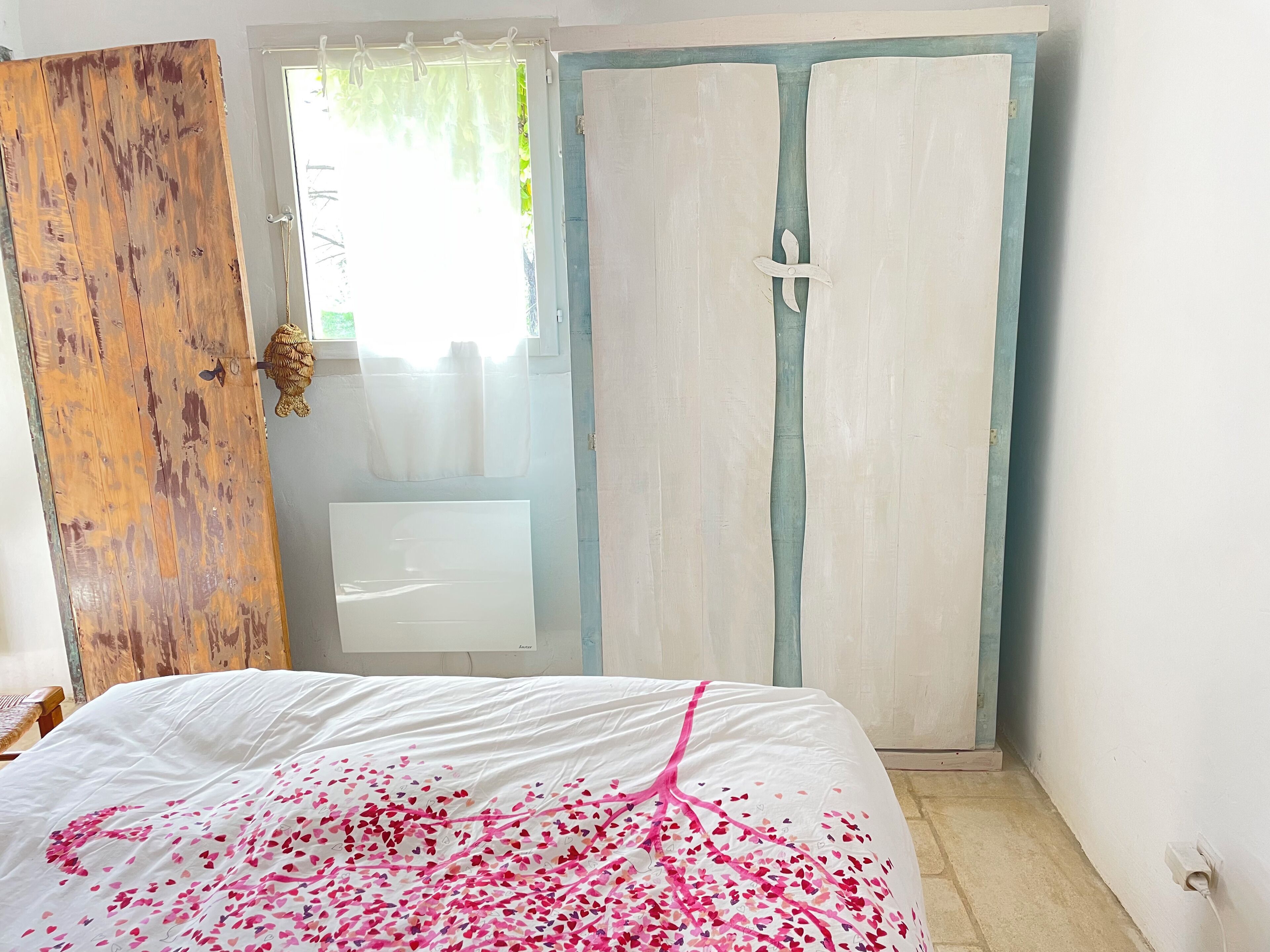 Ein Schlafzimmer mit einem Bett, einer Holztür und einem weißen Kleiderschrank.