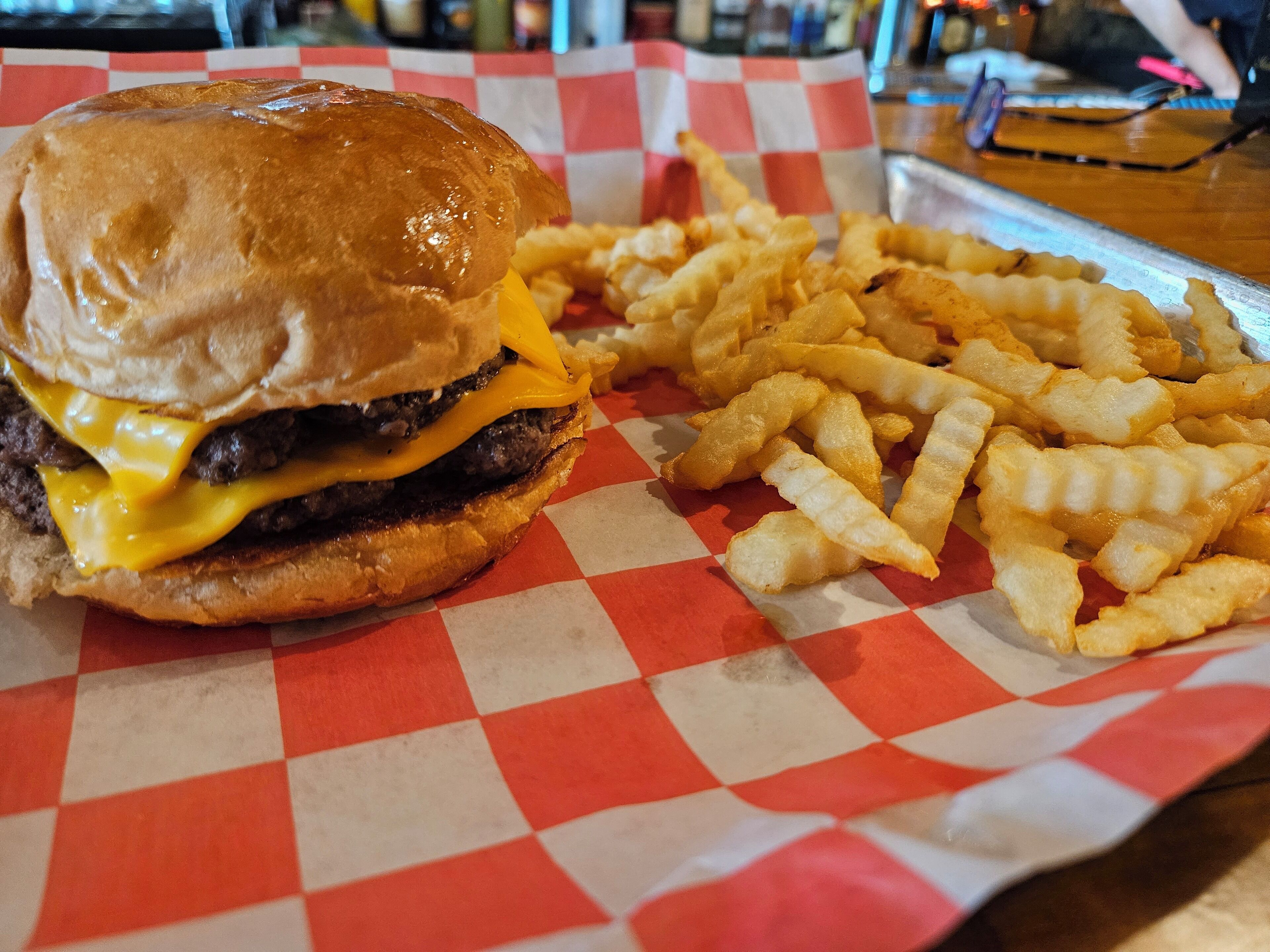 Una hamburguesa con papas fritas sobre un mantel a cuadros.