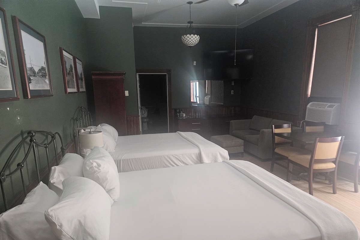 Habitación de hotel con dos camas, un escritorio, una silla y un televisor.