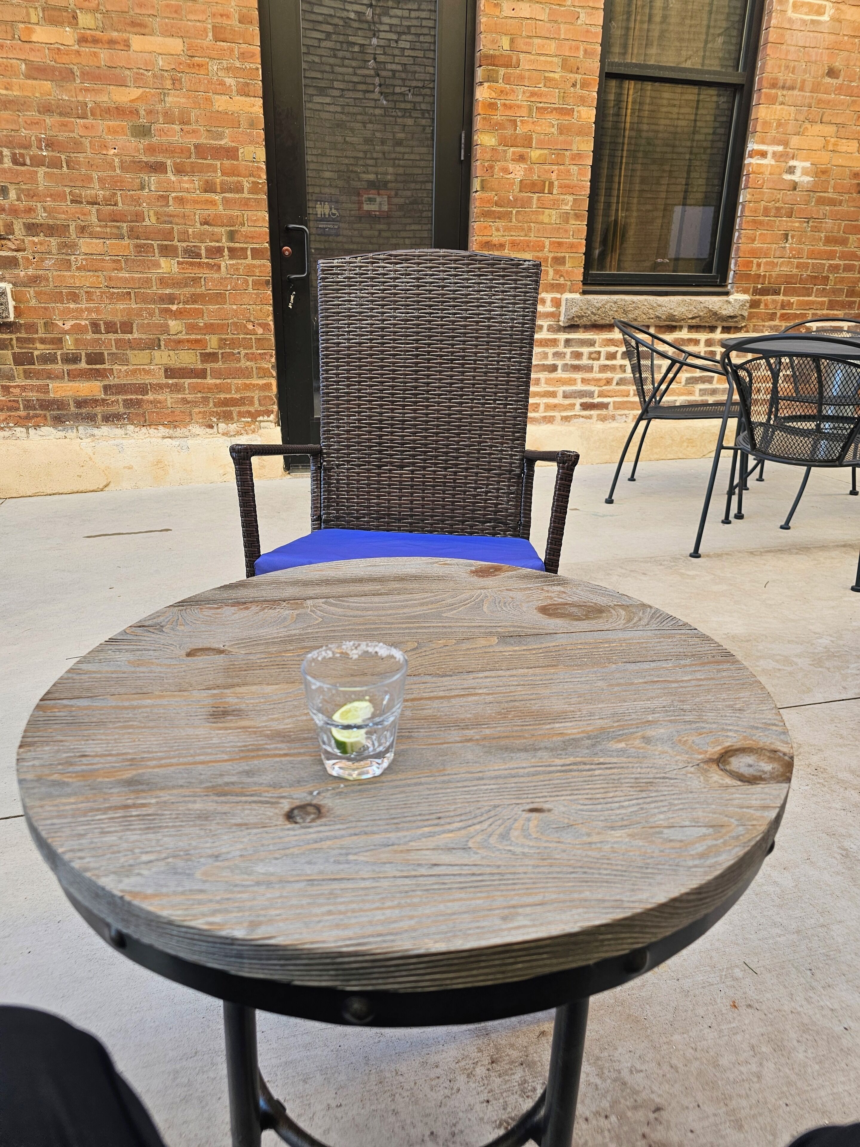 Une table ronde en bois, avec un verre d’eau et un coussin bleu.