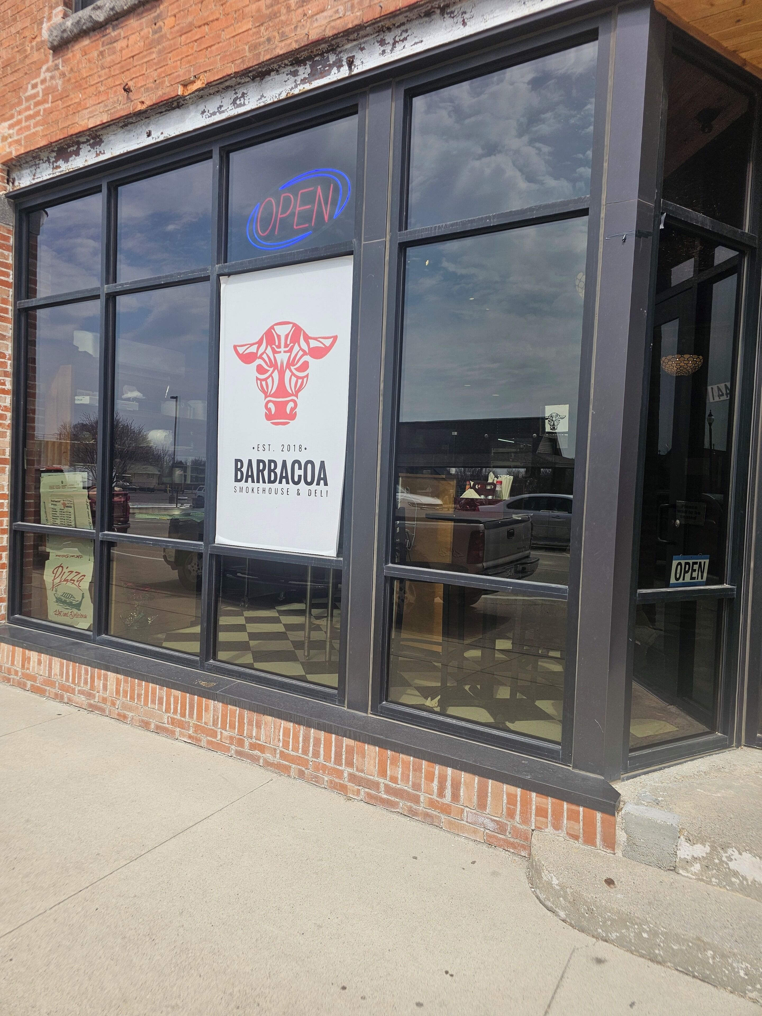 A storefront with a sign indicating it's open, a logo, and the name 'BARBACOA' suggesting a restaurant or deli.