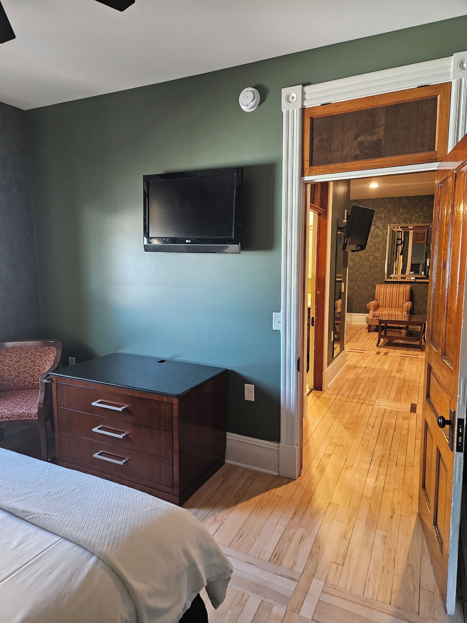 Une chambre à coucher avec un lit, une commode et un téléviseur fixé au mur.