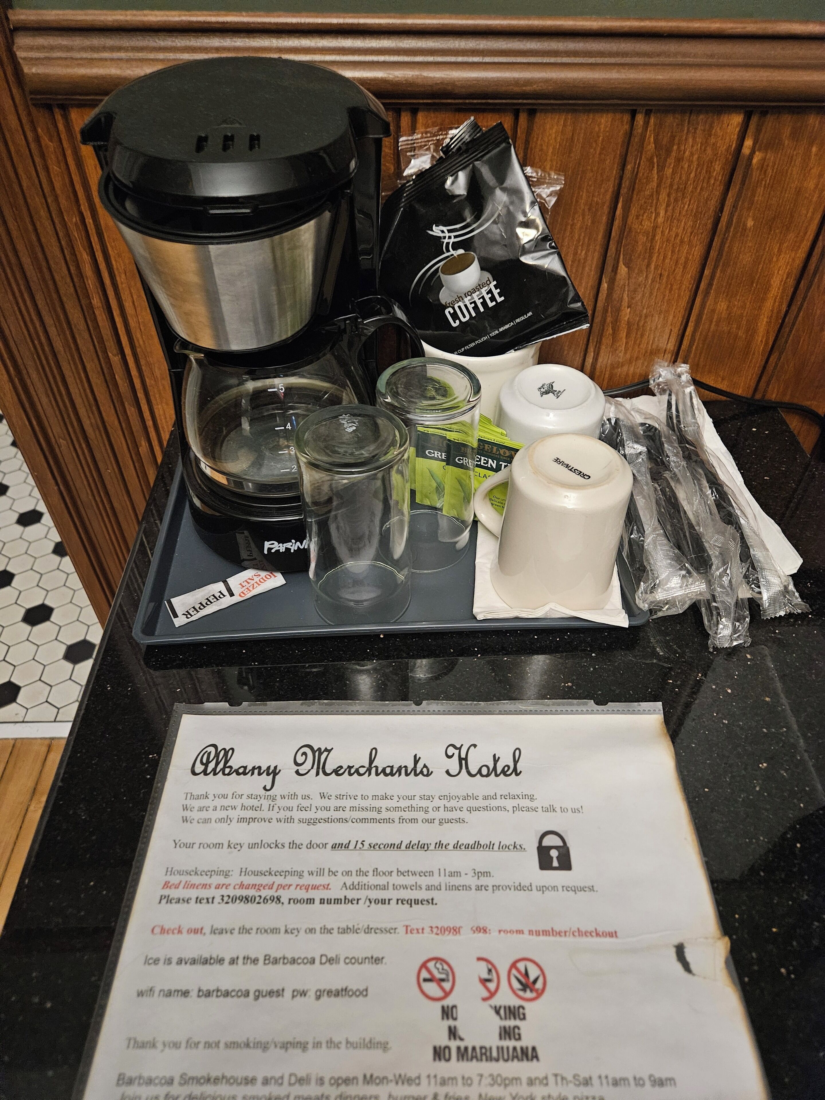 A coffee station with a coffee maker, cups, and coffee pods on a tray.
