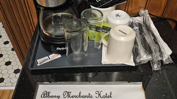 A coffee station with a coffee maker, cups, and coffee pods on a tray.