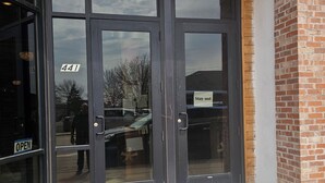 Een winkelgevel met grote glazen deuren, een houten plafond en een bakstenen muur.