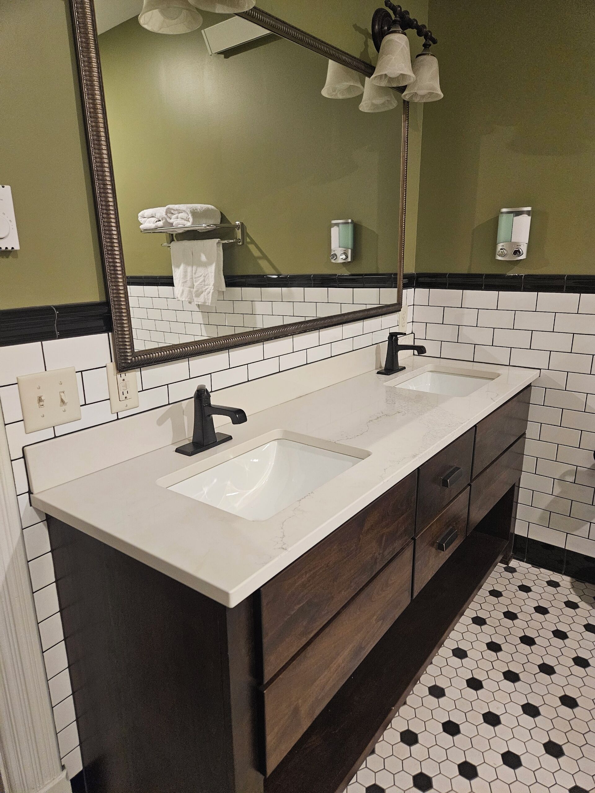 A bathroom with two sinks, a large mirror, and a towel rack.