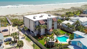 A multi-story building with a rooftop pool, surrounded by palm trees and a beach view. - La Mer on 10th - A Luxurious holiday stay! (St. Augustine Beach)