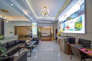 A hotel lobby with a reception desk, seating area, and a large wall display.