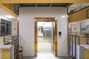 A corridor with a door leading to a room, a trash bin, and a handrail on the right. - Nanyou Hotel Lijiang Wangjiang Business Hotel (Lijiang)