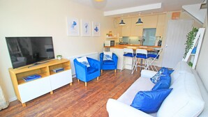 Un salon avec un téléviseur, un canapé et des fauteuils.