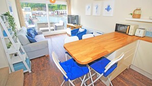 Un salon moderne avec une table à manger en bois, des chaises rembourrées bleues, un canapé et un téléviseur.