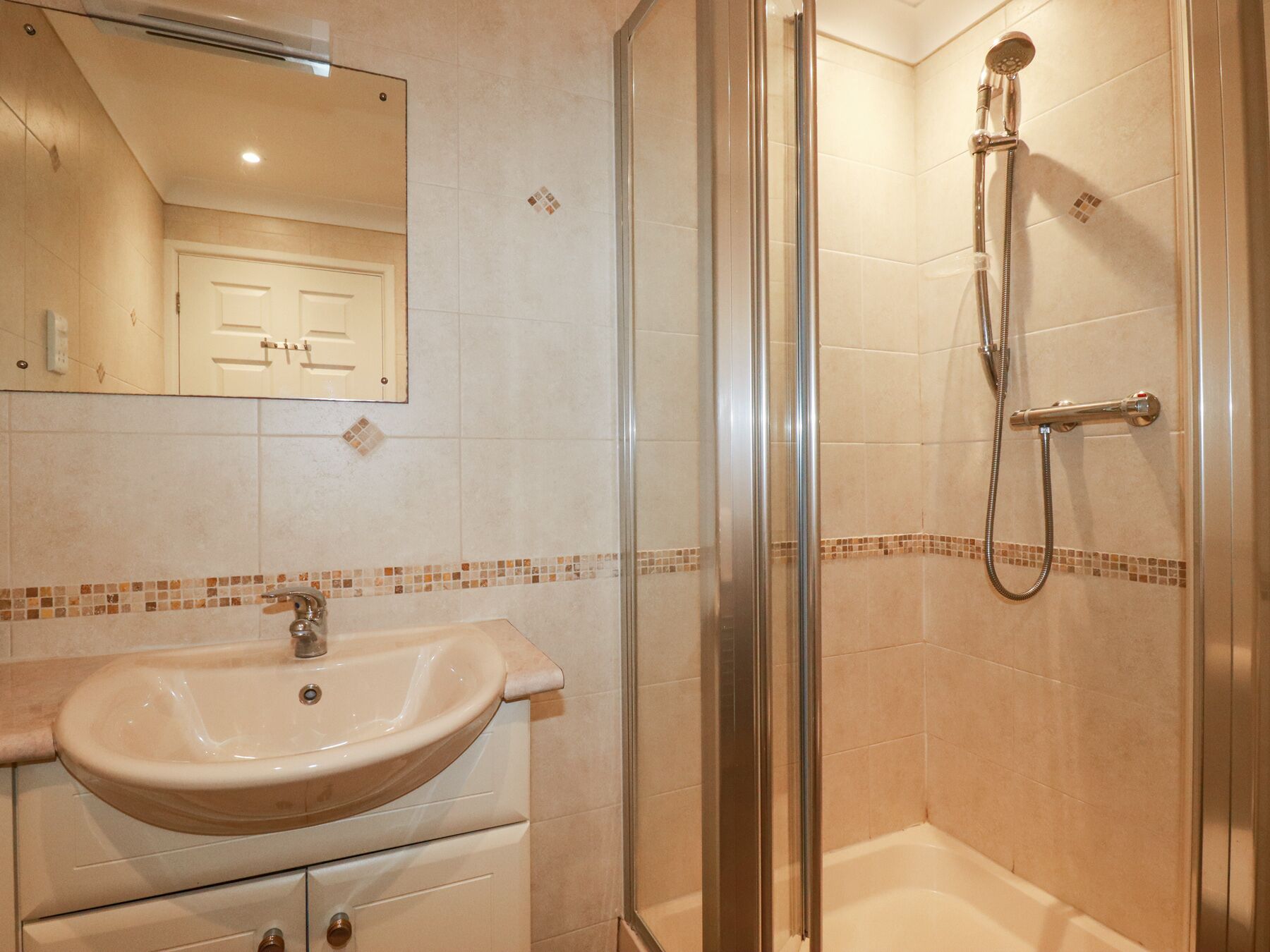 Une salle de bain avec une douche à parois de verre, un lavabo et un miroir.