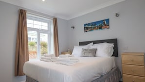 Quarto com cama, mesa de cabeceira, cômoda e um quadro na parede.