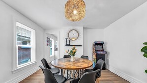A dining area with a round wooden table, black chairs, a vase with flowers, a wall-mounted mirror, and a ceiling light fixture. - 7bdrm, 3baths, 2 kitchens, mins to falls, Arcade, WiFi, AC, parking (Niagara Falls)