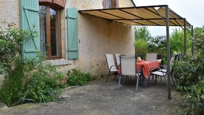A rustic stone building with a covered patio area featuring a table and chairs. - Farmhouse in Giroux Near Forest & Lake (Giroux)