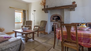 A cozy living room with a fireplace, wooden furniture, and a dining table. - Farmhouse in Giroux Near Forest & Lake (Giroux)