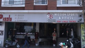 Un hotel con un letrero que dice "HOTEL PIZZA" y una tienda en la planta baja que anuncia "MISSION SPORTS & FITNESS".