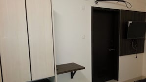 Una habitación con armario, estante pequeño, puerta y cama.