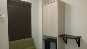 Una habitación con un sofá verde, un armario, una mesita y un cubo de basura.