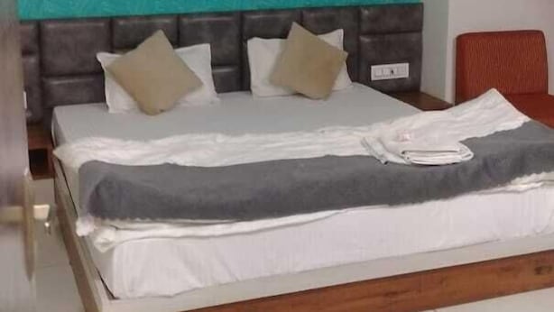 Un dormitorio con cama, ventilador de techo y pared verde azulado.