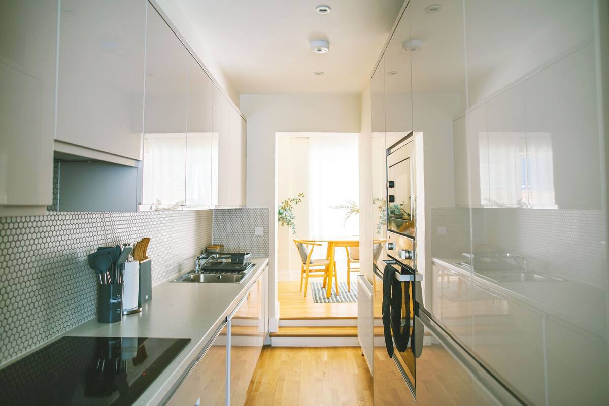 A modern kitchen with a central island, a dining area with a wooden table and chairs, and a view into the dining room.