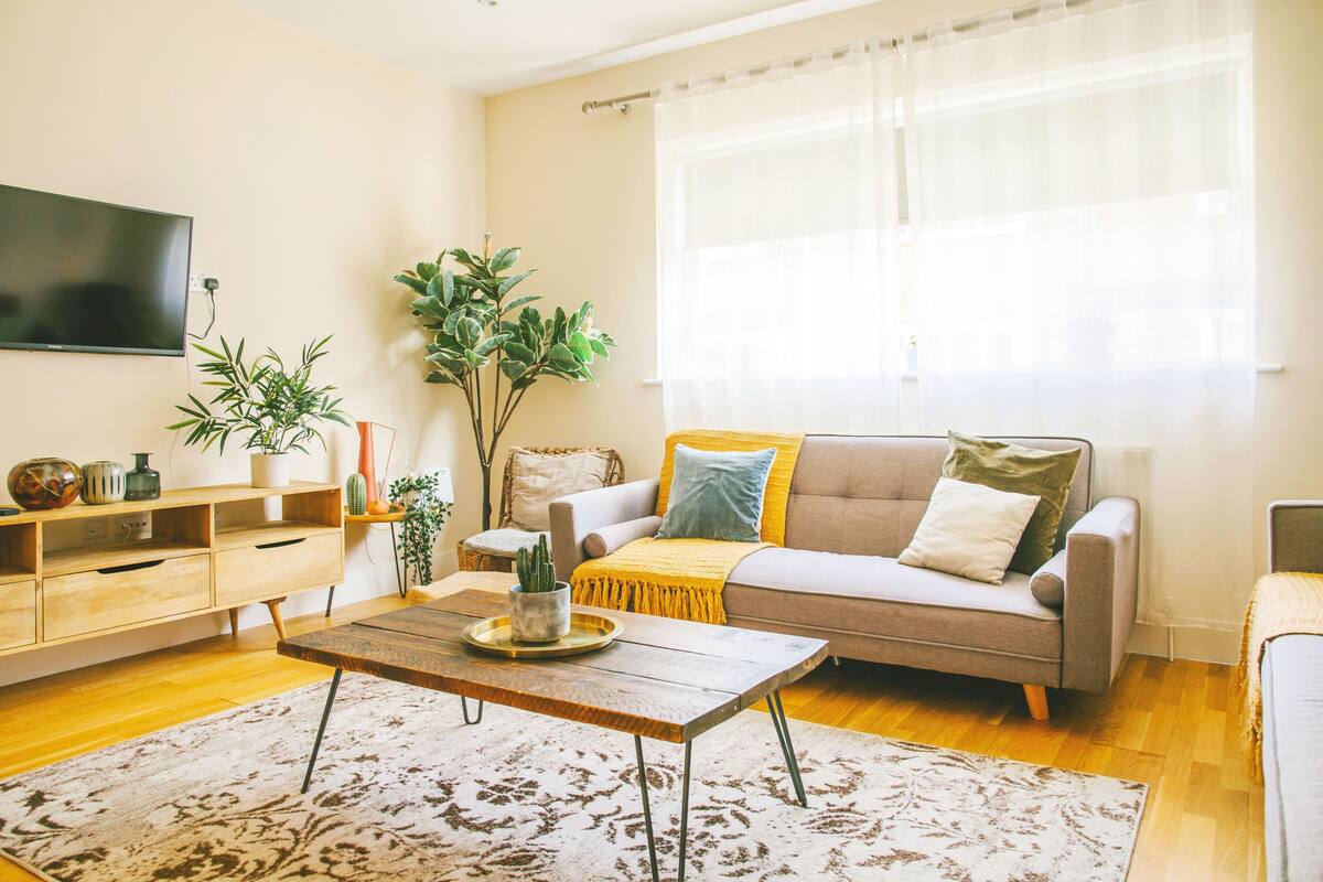 A living room with a sofa, coffee table, and a TV mounted on the wall.