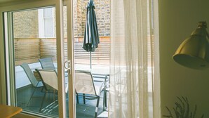 Una habitación con puerta corrediza de vidrio que da a un patio exterior con mesa y sillas.