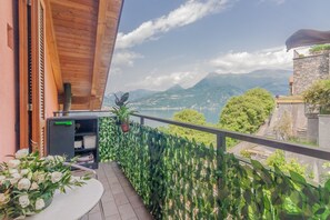 A balcony with a view of mountains and a lake, wooden ceiling, and potted plants. - Il Nido sul Lago in Perledo (Perledo)