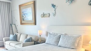 Quarto com uma cama grande, um sofá, uma mesa de cabeceira e decorações na parede, incluindo um quadro emoldurado e um objeto decorativo.