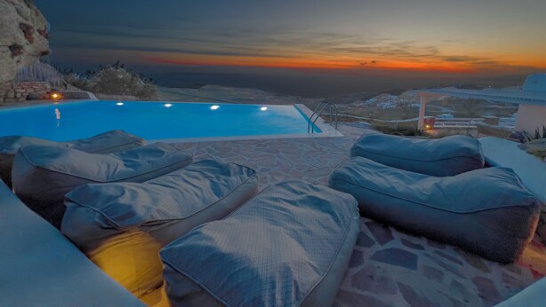 An infinity pool with a sunset view, outdoor seating with cushions, and a stone patio. - Villa Prive 88 Mykonos (Mykonos)